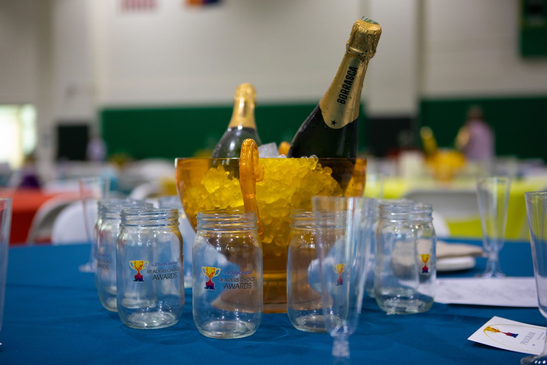 A bottle of champagne is in a bucket of ice on a table.