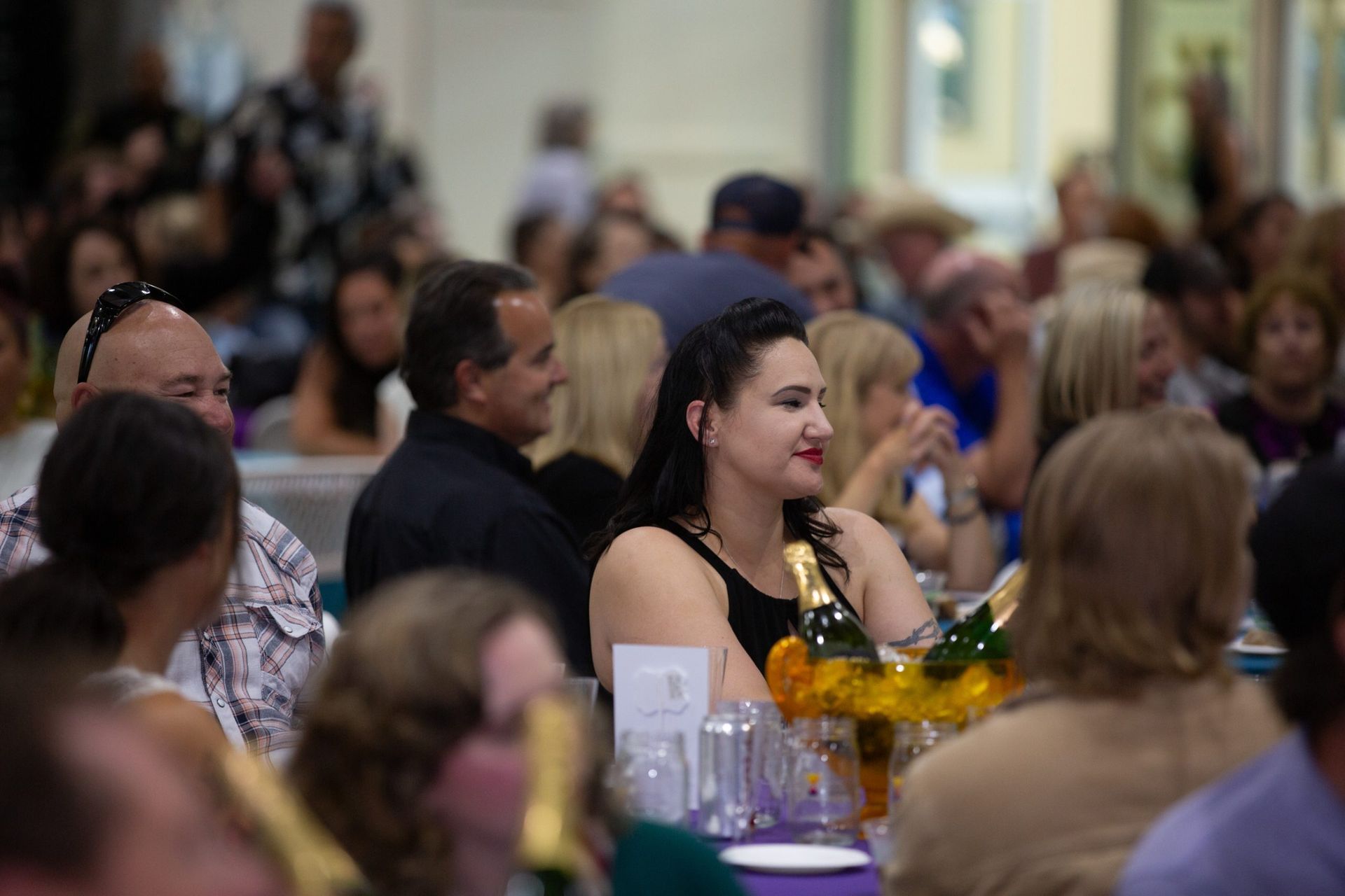 A woman is sitting at a table in a crowded room.