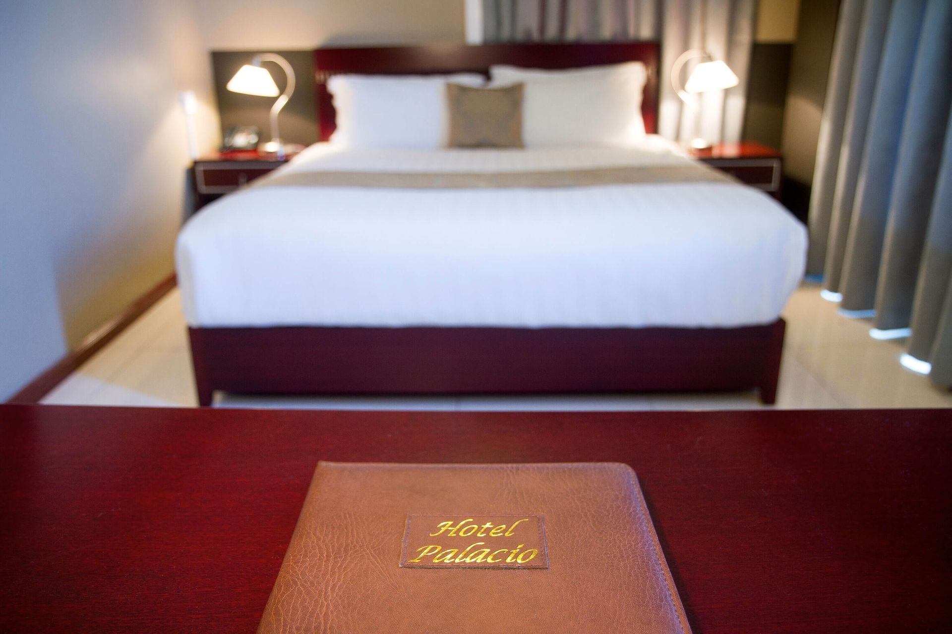 Hotel room with a bed in the background, a red desk in the foreground with a 