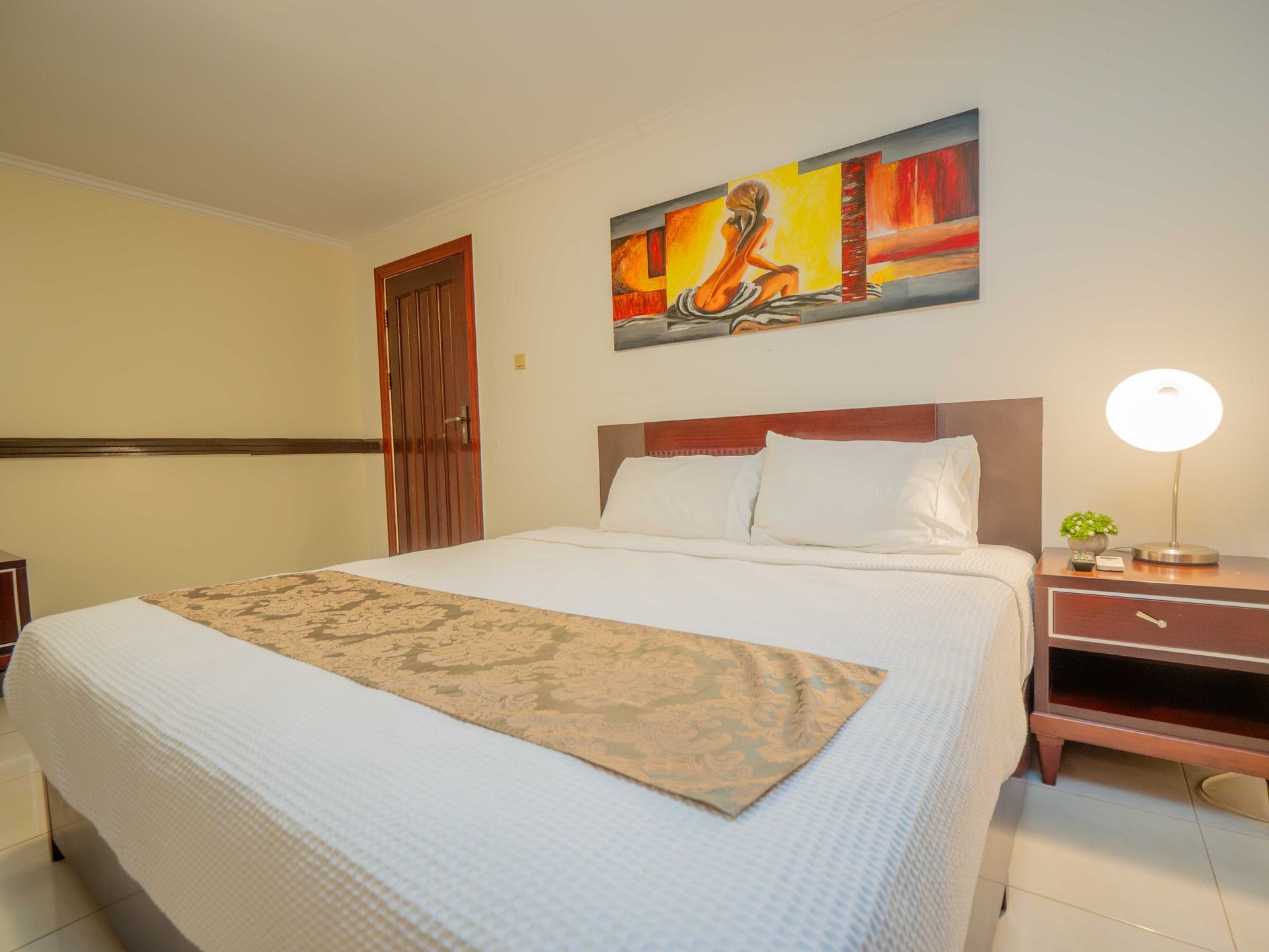 Bedroom with a double bed, nightstand, artwork, and a door.
