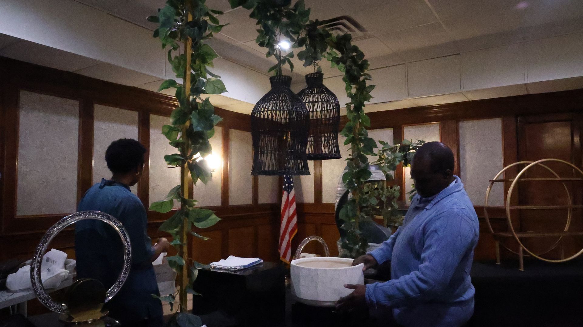 A man and a woman are standing in a room with a bird cage in the background.