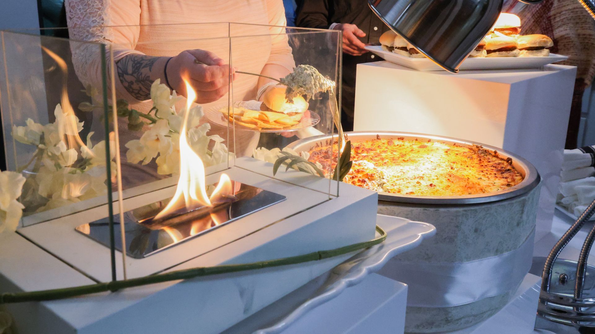 A person is holding a plate of food in front of a fireplace.