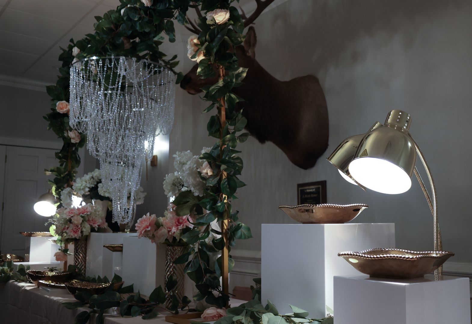 A deer head with a chandelier hanging from it