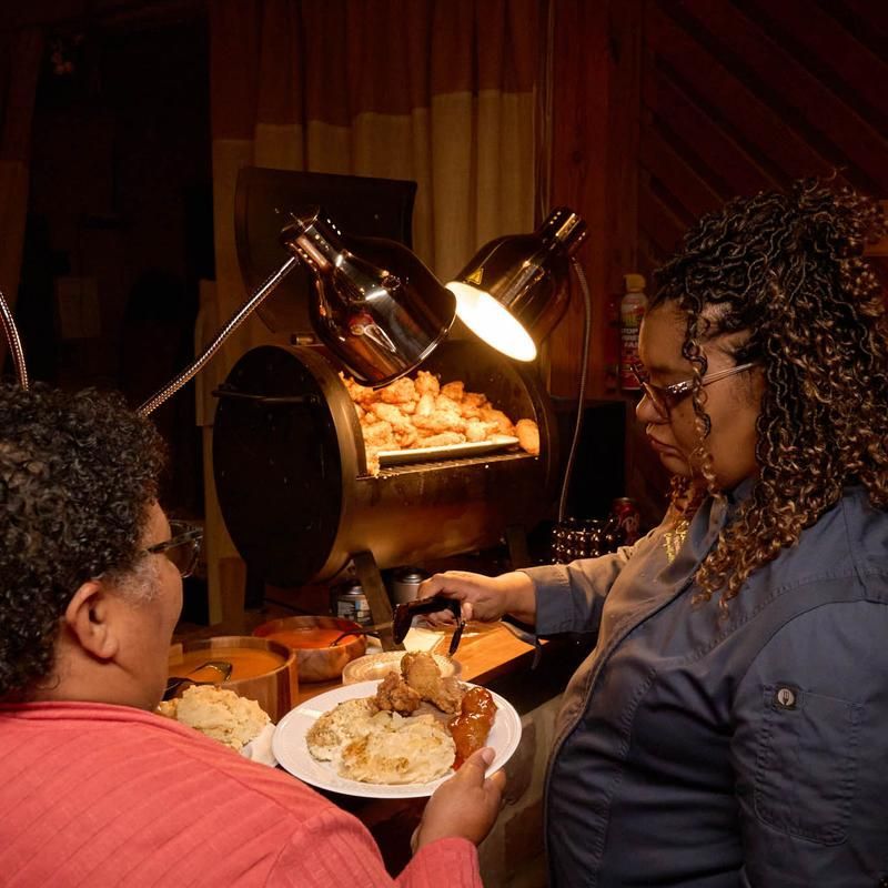 A woman is holding a plate of food next to another woman