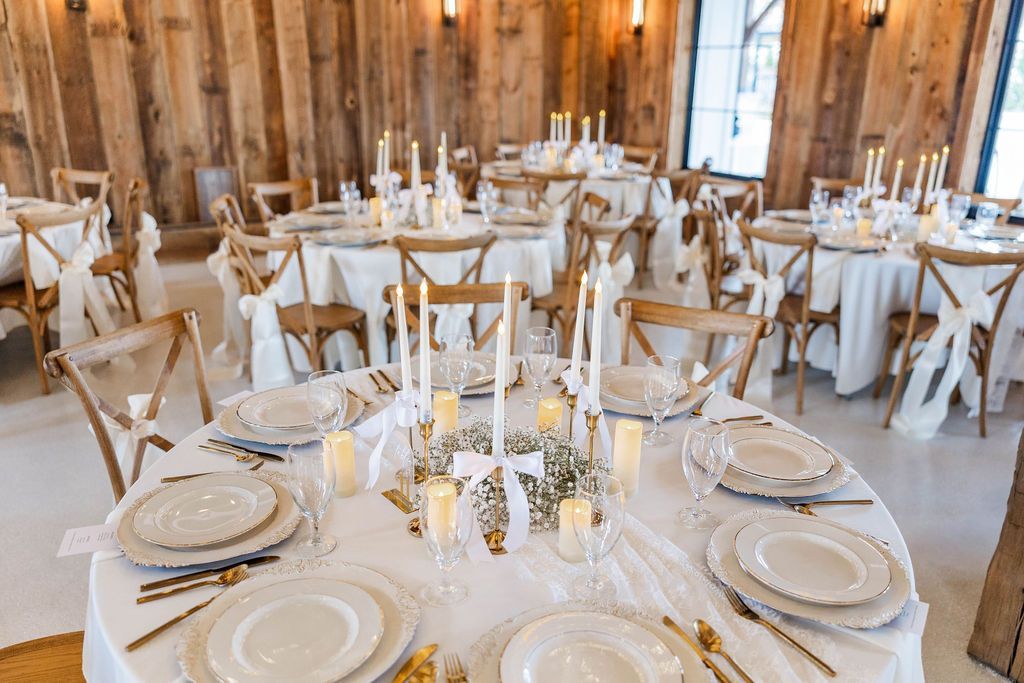 Barn interior with large wooden beams, open doorway, and wedding decor.