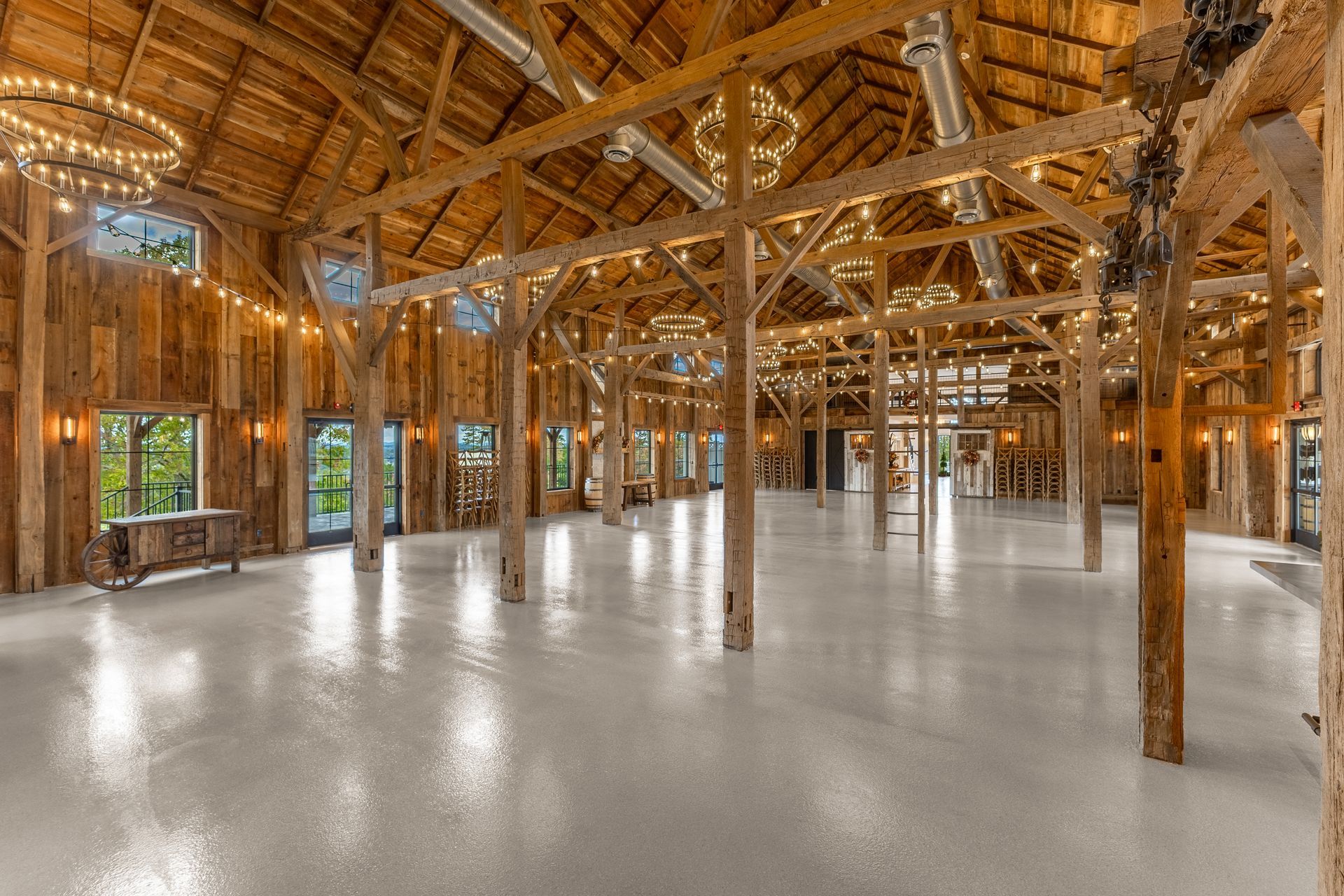 Spacious barn interior with wood beams, string lights, and a glossy white floor.