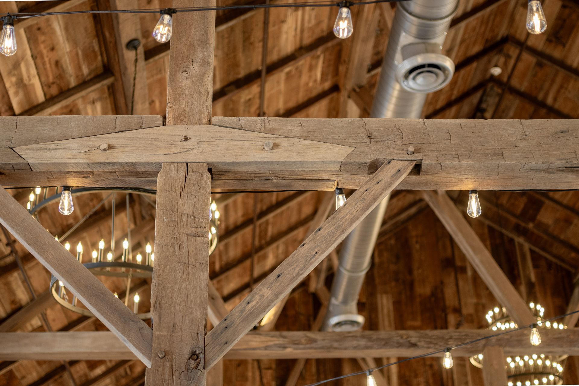 Wooden barn beams with string lights, ventilation duct.