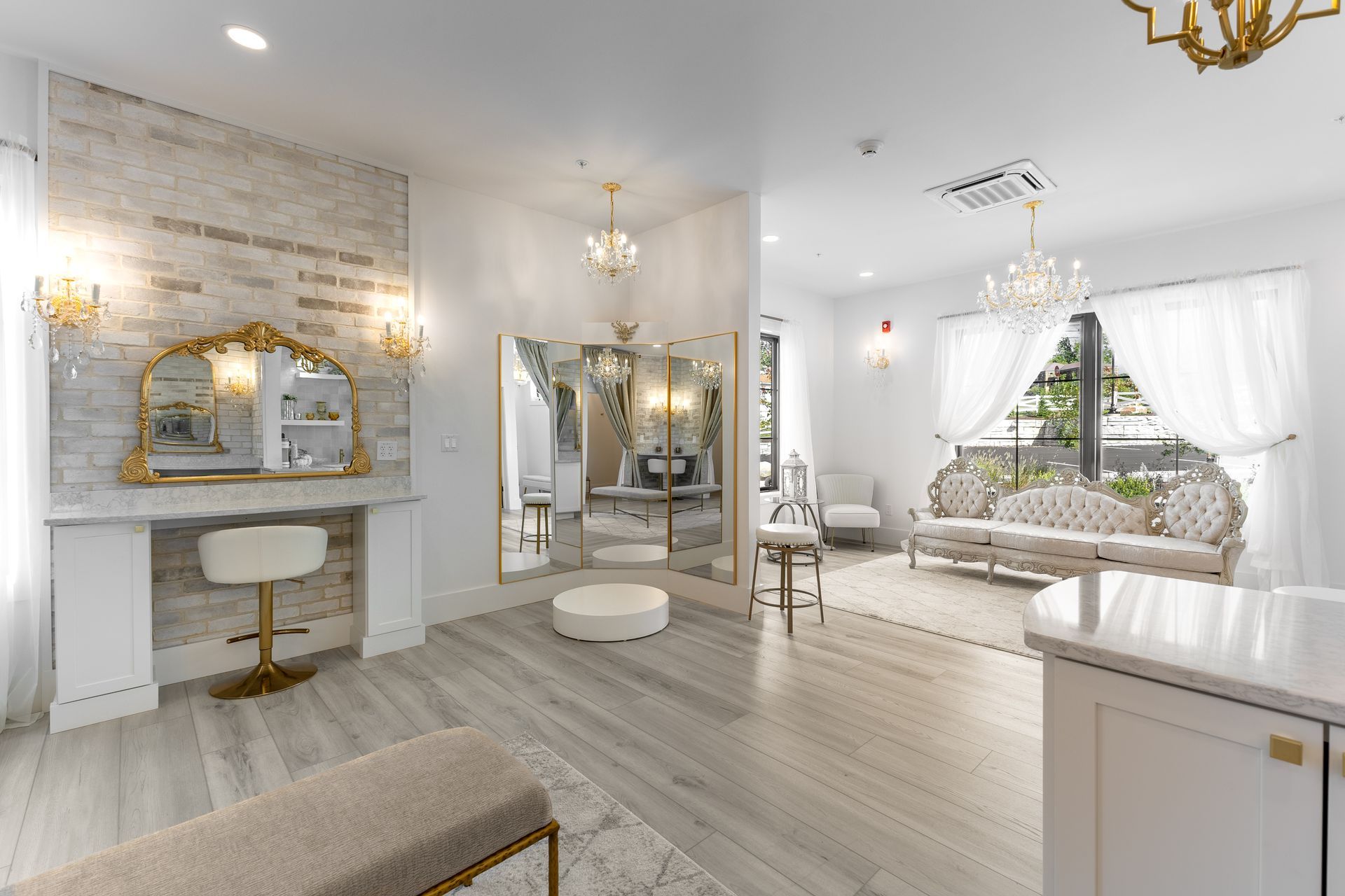 Elegant bridal boutique interior with mirrors, seating, chandeliers, and marble accents.