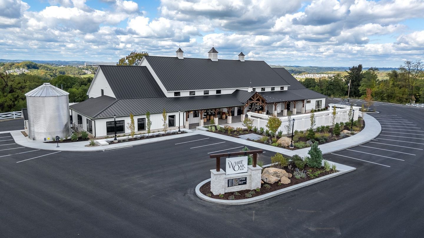 A stunning reclaimed barn wedding venue white barn with a black roof.