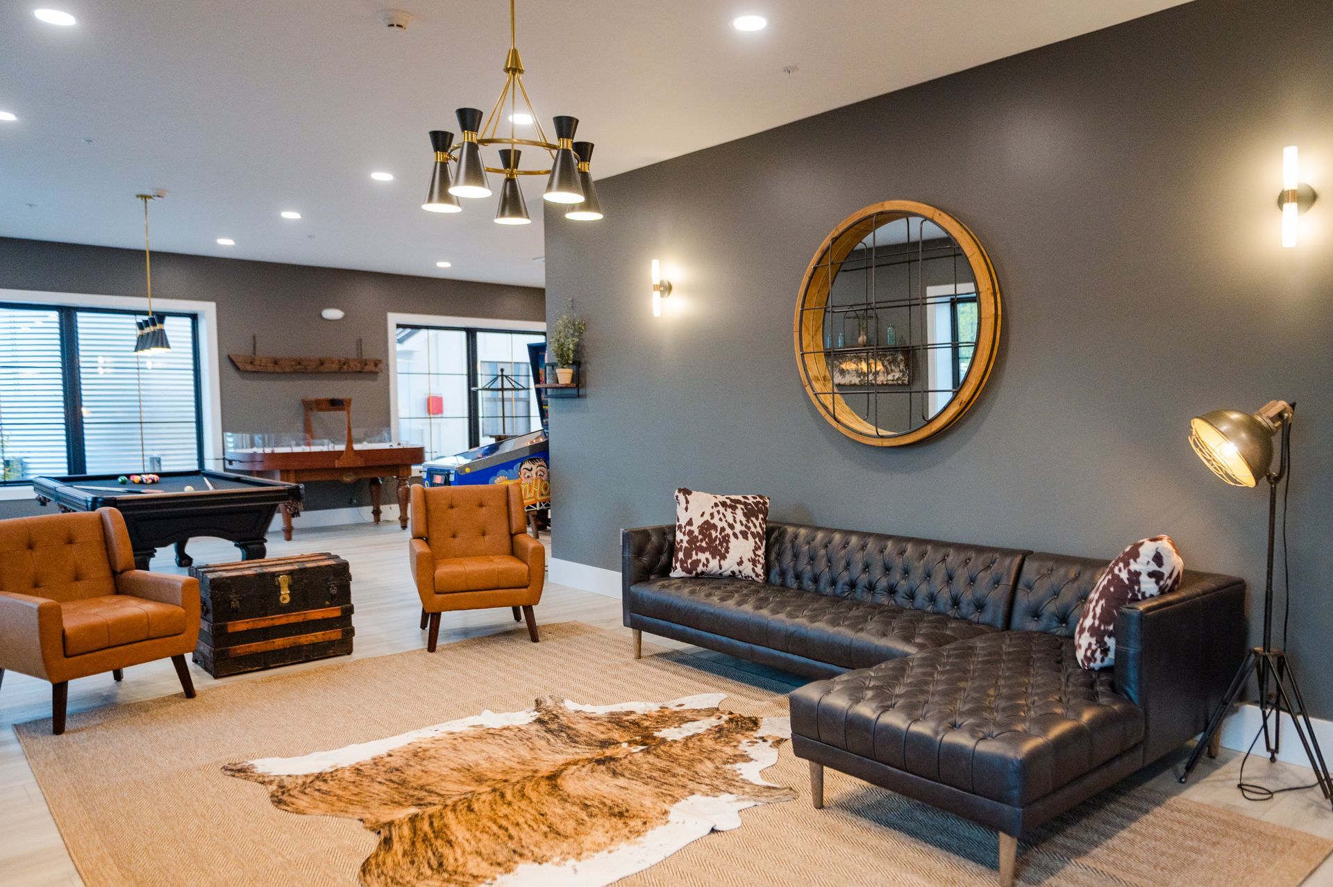 Groom's suite/Lounge with a leather sectional, animal hide rug, pool table, and gold accents against gray walls.