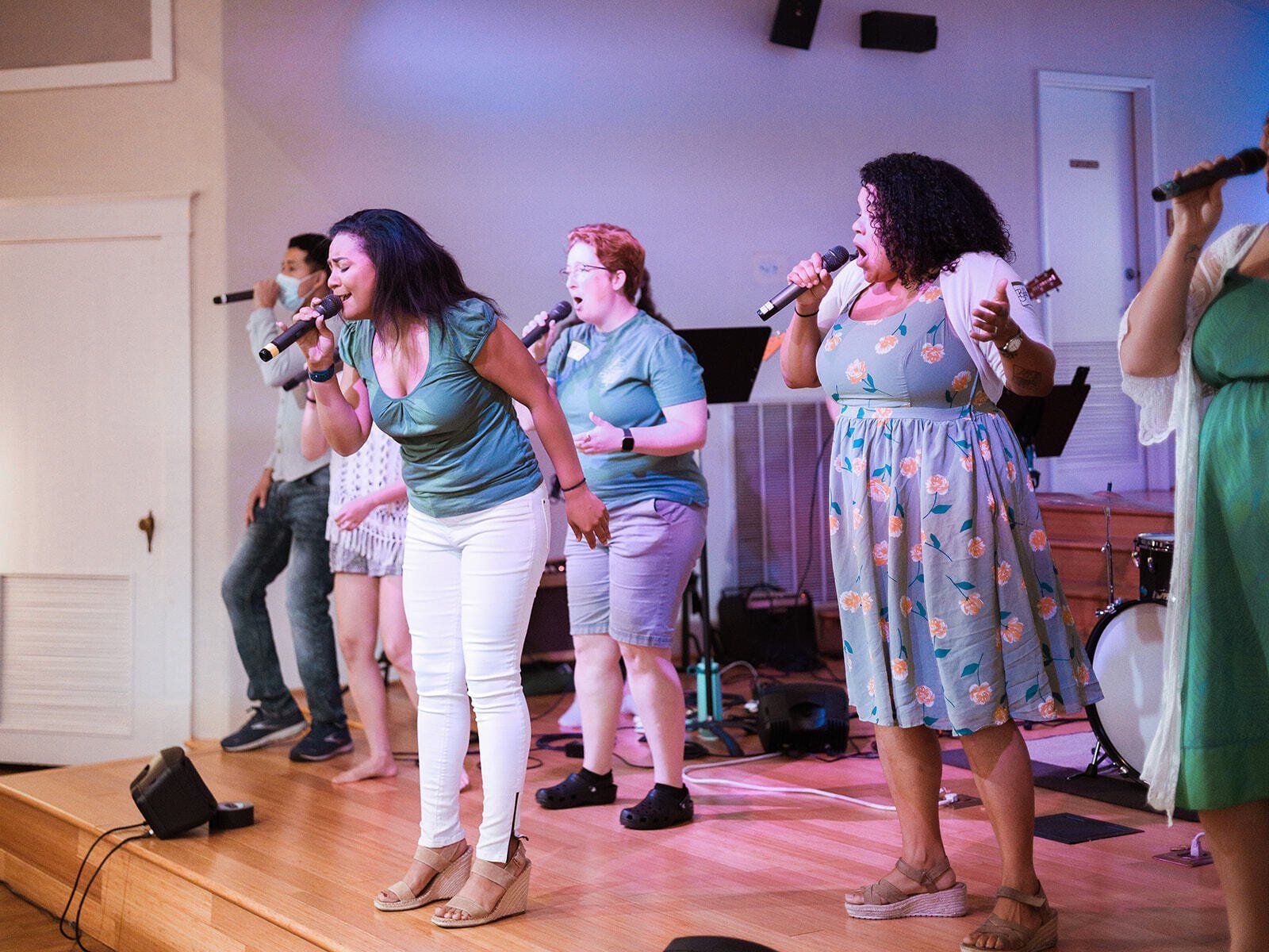 A group of women are singing into microphones on a stage.
