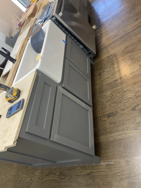 A kitchen with gray cabinets and a white sink