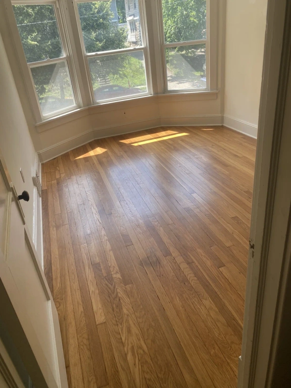 A room with hardwood floors and a bay window.