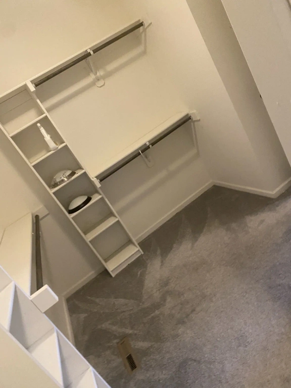 A walk in closet with a staircase leading up to it.