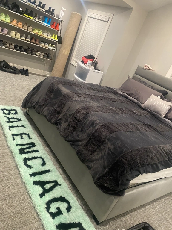 A bedroom with a bed and a rug that says balenciaga