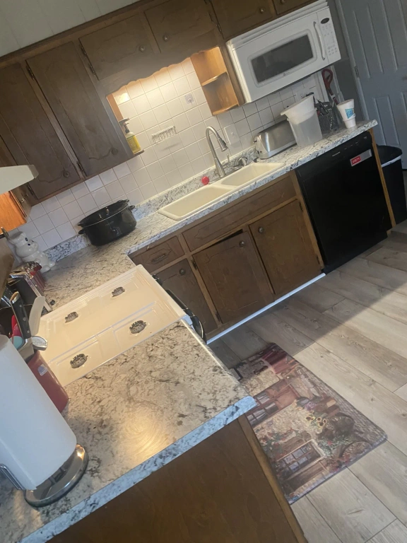 A kitchen with a stove , sink , microwave and dishwasher.