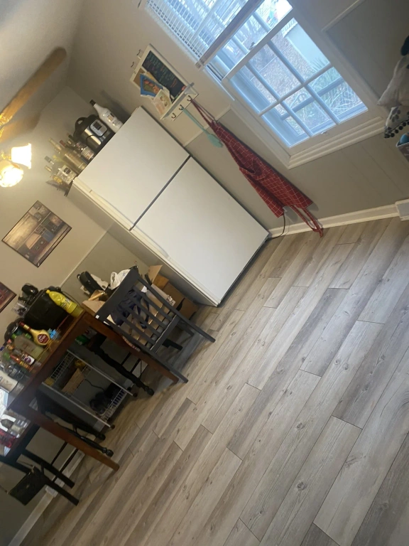 A kitchen with a table and chairs , a refrigerator , and a window.