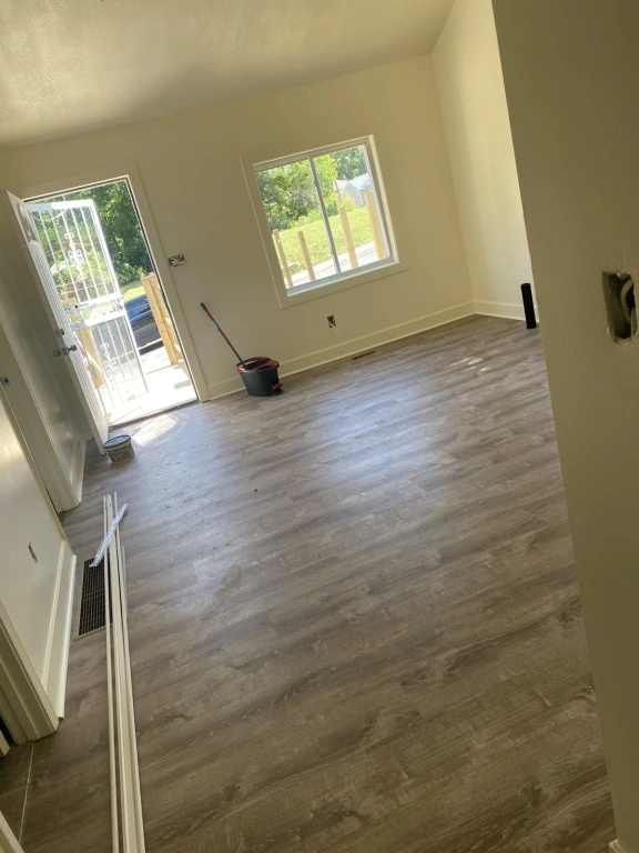 A living room with hardwood floors and a window.
