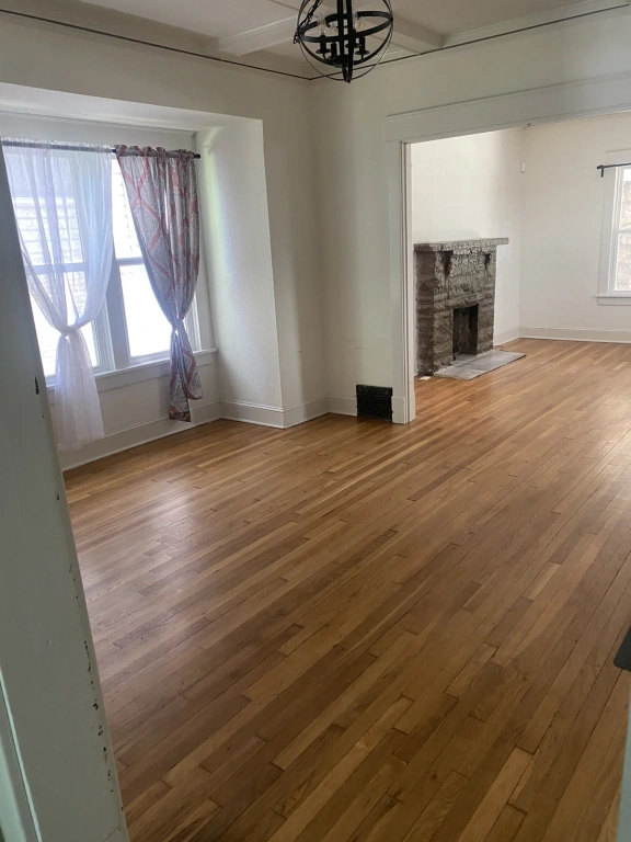 An empty living room with hardwood floors and a fireplace.