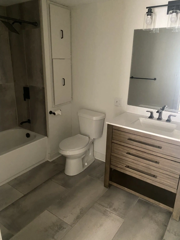 A bathroom with a toilet , sink , bathtub and mirror.