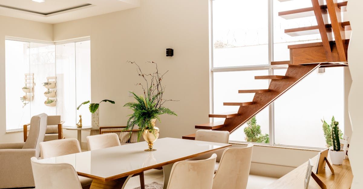 A dining room with a table and chairs and a wooden staircase.