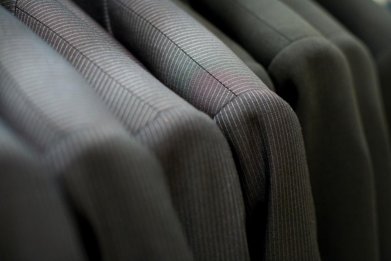 A close up of a row of suits hanging on a rack.