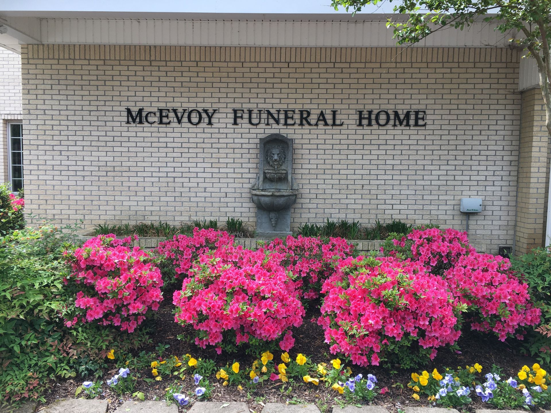 McEvoy Funeral Home exterior with brick wall, fountain, and flower bed.
