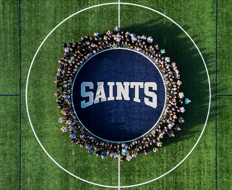 Aerial view: Group of people encircling a dark blue circle with 