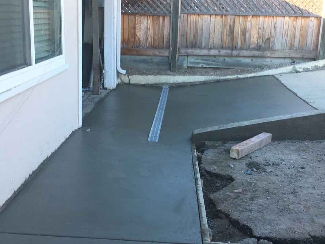 A concrete walkway is being built in front of a house.