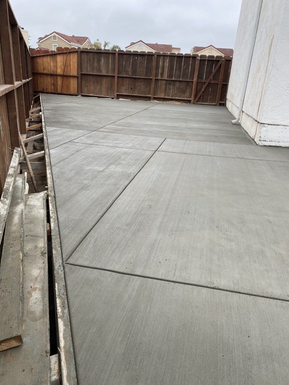 A concrete walkway is being built next to a wooden fence.