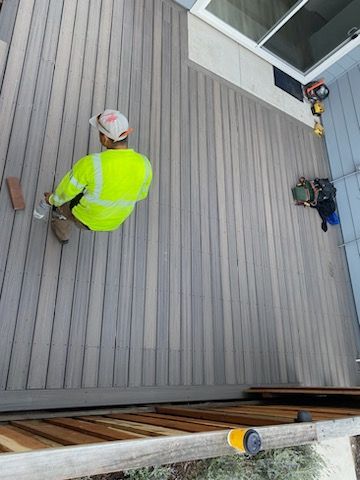 A man is kneeling down on a wooden deck.