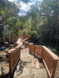 A wooden bridge is being built over a set of stairs leading up to a house.
