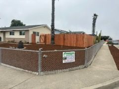 A chain link fence is being installed in front of a house.