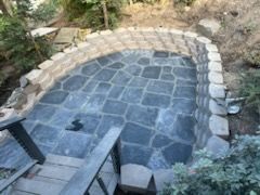 A stone patio with stairs leading up to it and a stone wall surrounding it.