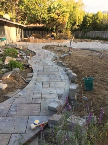 A brick walkway is being built in a backyard.