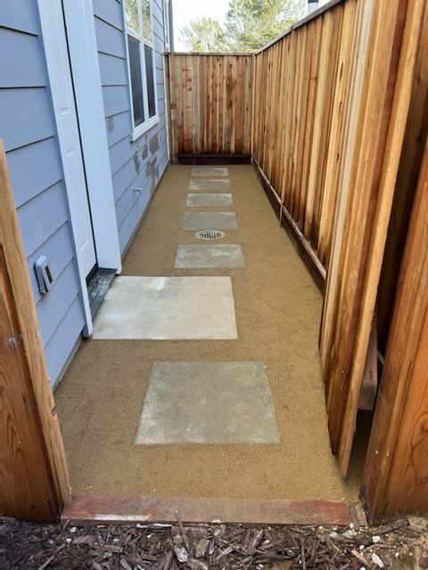 A walkway leading to a house with a wooden fence