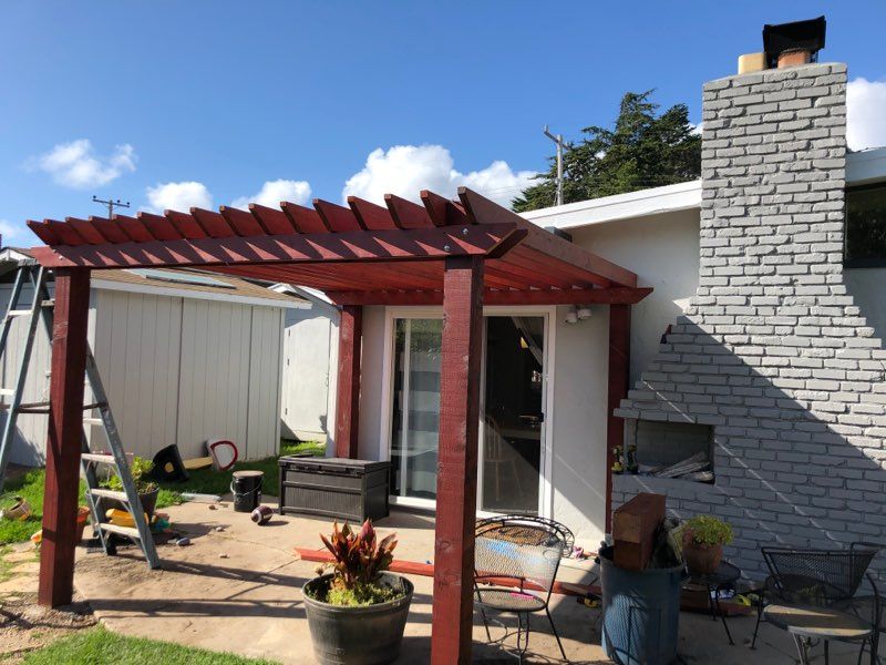 A white house with a red pergola in front of it