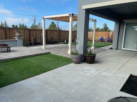 A patio with a pergola and potted plants in front of a house.