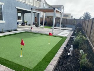 There is a putting green in the backyard of a house.