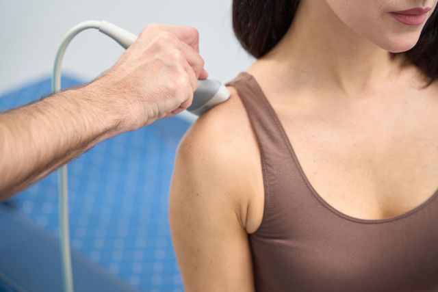 A woman is getting an ultrasound on her shoulder.
