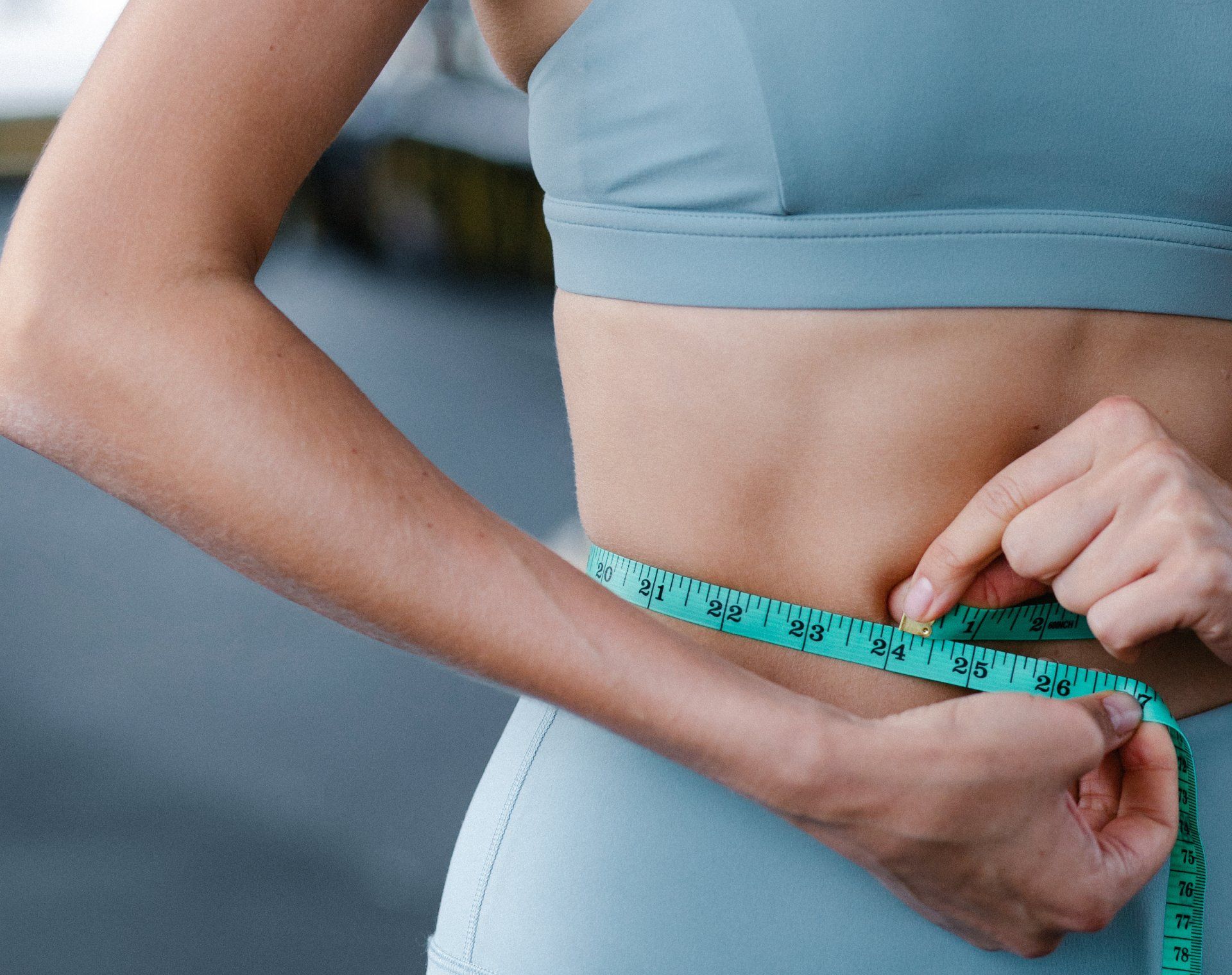 a woman is measuring her waist with a tape measure .