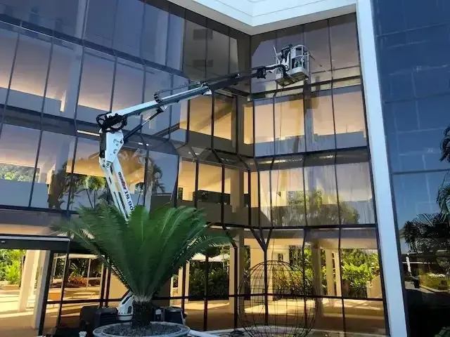 A Crane is Cleaning the Windows of a Large Building — Coastal Arborist Services in Whitsundays, QLD