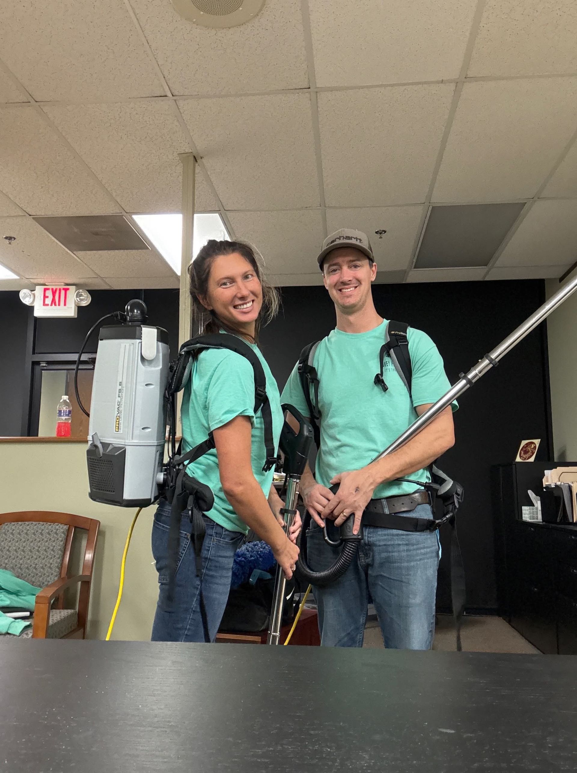 A man and a woman are standing next to each other holding a vacuum cleaner.