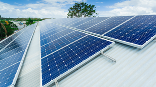 There are many solar panels on the roof of a building.