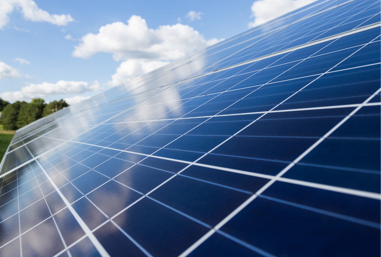 A row of solar panels against a blue sky with clouds