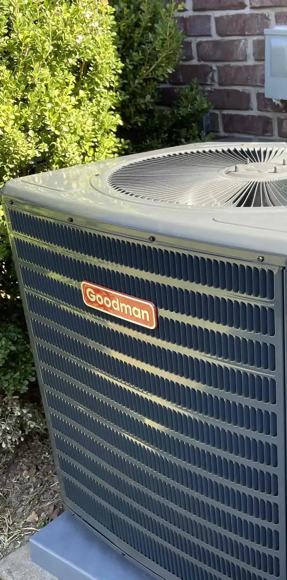 Goodman air conditioner unit outside a brick building.