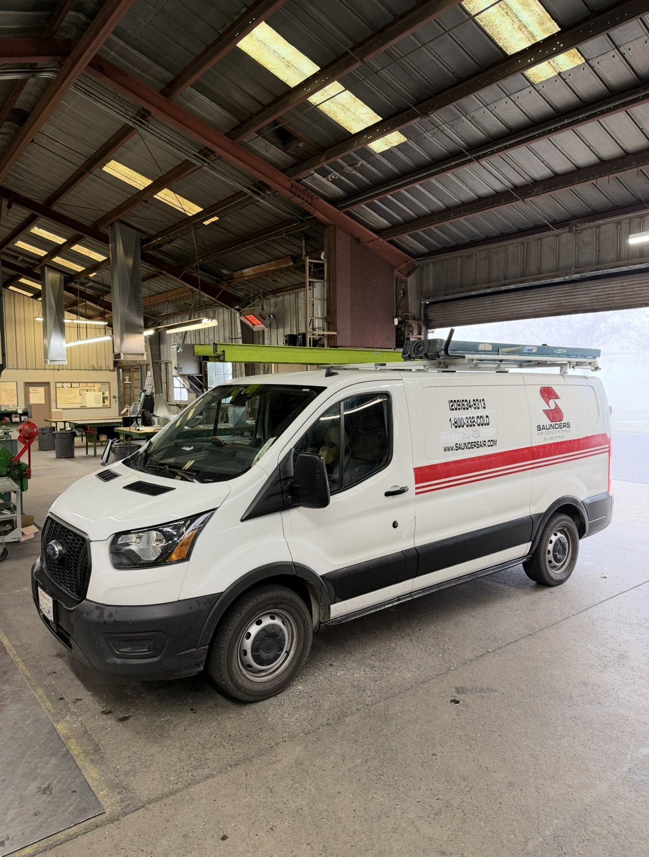 Black and white industrial exterior with ventilation ducts and windows against a striped wall.
