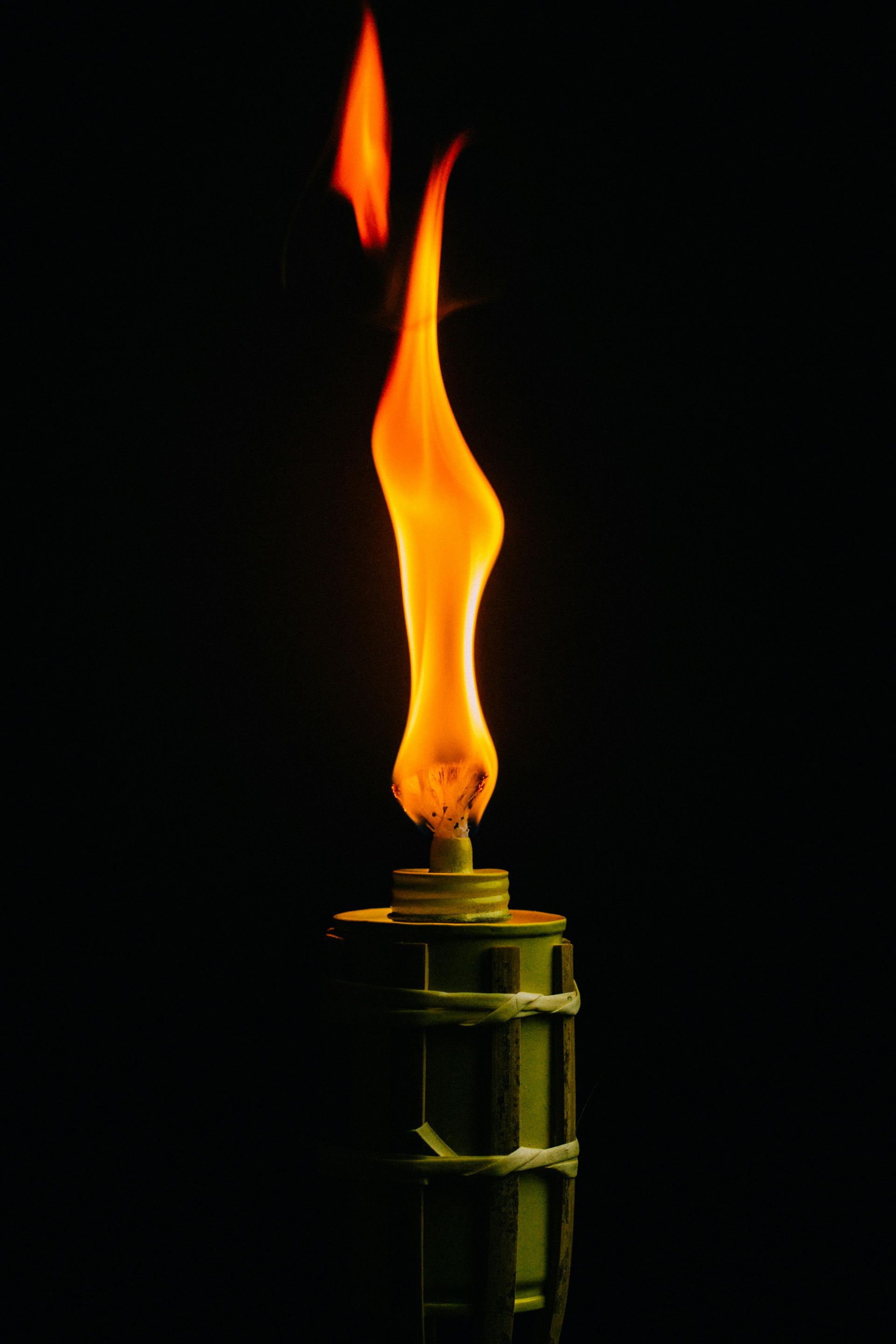 Torch with an orange flame, lit against a black background.