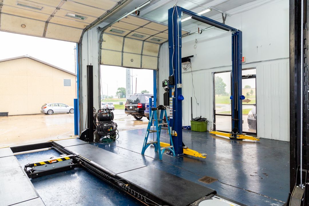 A car is being worked on in a garage with two lifts.