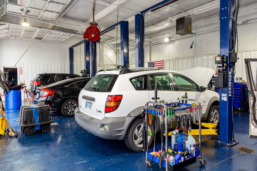A white suv is sitting on a lift in a garage.